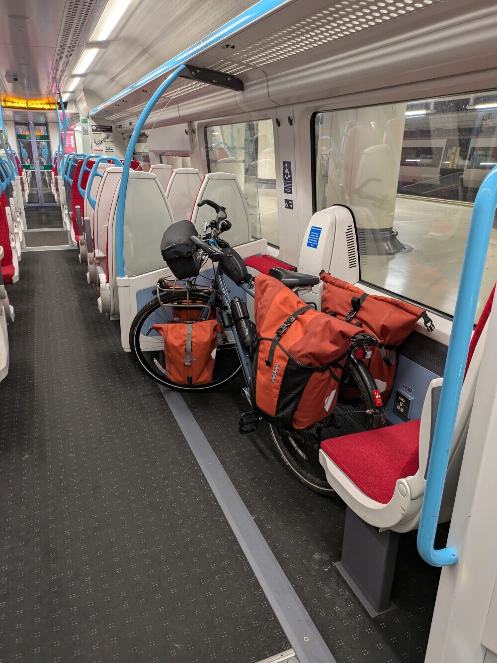 My bike on a UK train. You can see my four panniers (red) and the handlebar and top-tube bags (black)
